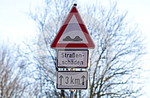 Pothole sign warning car driver at road damages german text translation `road damaged`