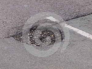 Pothole in tarmac road surface photo