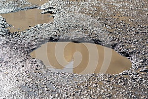 Potholes on asphalt road filled with water