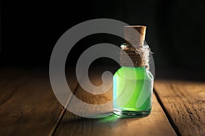 Potion in magic bottle on black and wooden background. Copy space. Selective focus