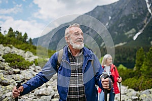 Potrait of active senior man hiking with wife in autumn mountains.