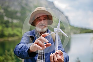 Potrait of active senior tourist holding a model of wind turbine.