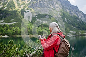 Potrait of active senior woman hiking in autumn mountains.