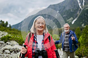 Potrait of active senior woman hiking with husband in autumn mountains.