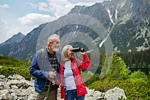 Potrait of active senior woman hiking with husband in autumn mountains.