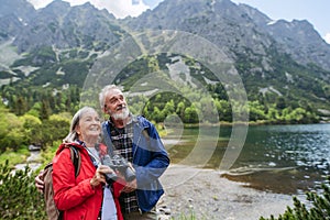 Portrét aktívnej staršej ženy na turistike s manželom v jesenných horách.