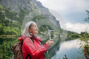 Potrait of female senior tourist holding a model of wind turbine.