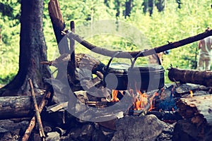 Pots, covered with soot, are hanging over a campfire