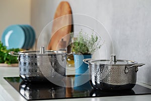 Pots with lids on cooktop in kitchen. Cooking utensils