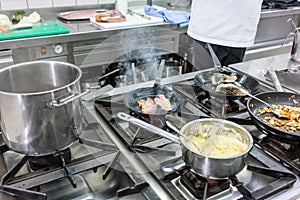 Pots and pans on stove in restaurant kitchen, the chef working i