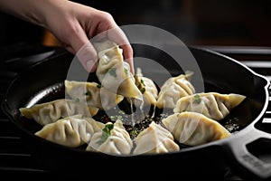 a potstickers being flipped by a hand in a cast iron pan