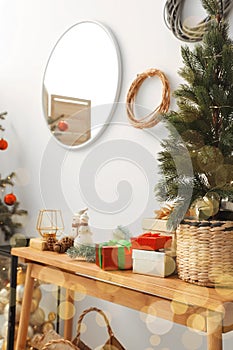 Potted fir tree and gift boxes on wooden table indoors. Christmas decoration