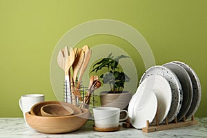 Potted plant and set of kitchenware on white marble table. Modern interior design