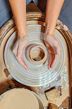 potter clay pottery pot craft wheel hands. Potter's hands while working on the wheel, top view with dark background.