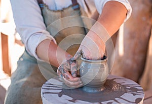 Potter is creating earthenware on potter`s wheel.