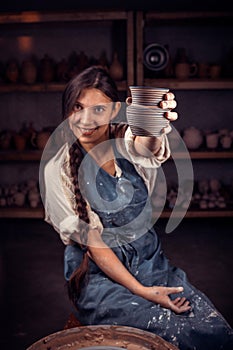 Potter female admires the work done in a pottery workshop. Pottery workshop.