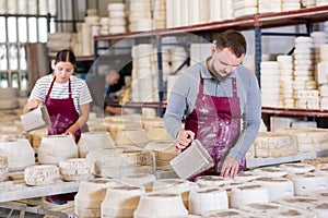 Potter filling casting molds with slip to shape ceramic products