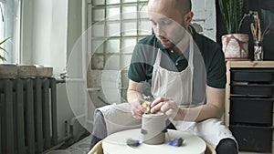 Potter handles sponge bottom circles of clay in the workshop.