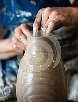 Potter hands making in clay on pottery wheel. Potter makes on the pottery wheel