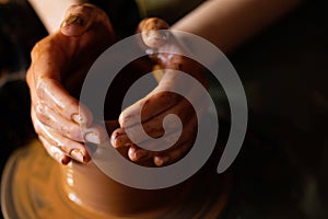 A potter hands moulding a clay pot on rotating potter`s wheel