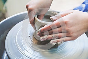 Potter hands working with clay on pottery wheel