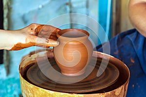 Potter makes on the pottery wheel clay pot. Hand of the master close-up during work. Ancient national craft