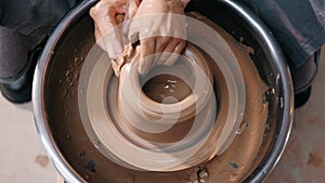 Potter making ceramic pot on the twisted pottery wheel. Top view. Potter at work, close up. Handmade, craft. Clay.