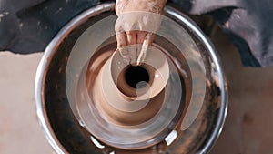 Potter making ceramic pot on the twisted pottery wheel. Top view. Potter at work, close up. Handmade, craft. Clay.