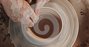 Potter making ceramic pot on the twisted pottery wheel. Top view. Potter at work, close up. Handmade, craft. White clay