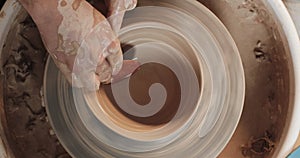 Potter making ceramic pot on the twisted pottery wheel. Top view. Potter at work, close up. Handmade, craft. White clay