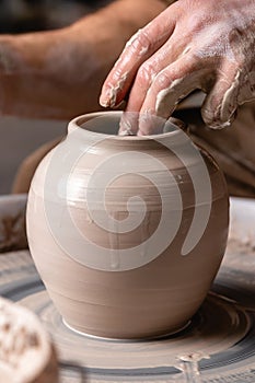 Potter making a jar or pot of white clay on the wheel circle in studio. concept of creativity, art and manual work