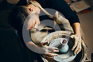 Potter modeling ceramic pot from clay on a potter`s wheel