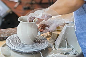 the Potter molds a pot from clay on a Potter's wheel. The master's hands make a pot on the potter's wheel.