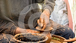 Potter`s hands creating a clay vase on a circle.