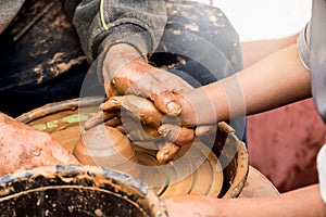 Potter`s hands creating a clay vase on a circle.