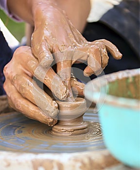 The potter`s hands are gently and surely formed by a clay pot on a potter`s wheel