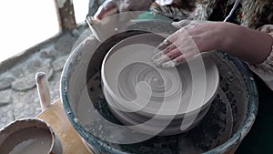 The potter`s hands are involved in the process of creating a clay product