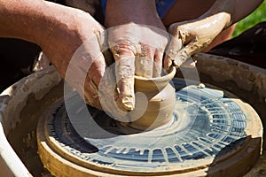 Potter`s hands make a clay bowl on a pottery wheel