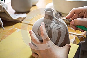 Potter`s hands make a decorative pattern on vase
