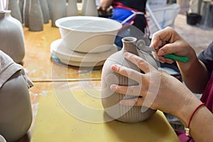 Potter`s hands make a decorative pattern on vase