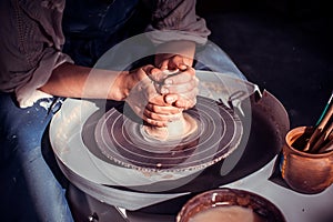 Potter`s hands and potter`s wheel. Close-up.