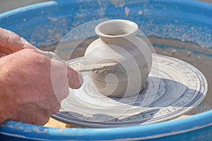Potter`s hands put pattern on jug on potter`s wheel
