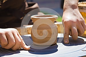 Potter`s hands separate a clay bowl from a pottery wheel with a thread