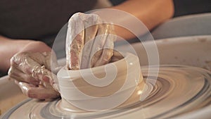 The potter`s hands are shaped a cup from a clay. The process