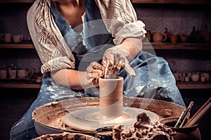 Hands of the master potter and vase of clay on the potter`s wheel close-up. Master crock. Twisted potter`s wheel. photo