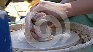 Potter`s hands work with clay on a potter`s wheel