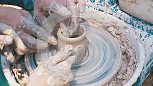 Potter`s hands work with clay on a potter`s wheel