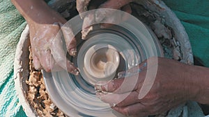 Potter`s hands work with clay on a potter`s wheel