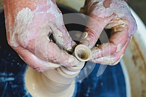 Potter`s hands at work while making a pitcher of clay on a potter`s wheel_