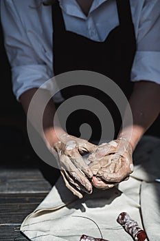 The potter`s woman hands are shaping a cup from a clay. The process of creating pottery. The master ceramist works in